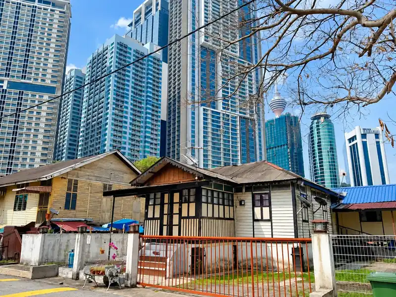 Rumah kayu tradisional di Kampung Baru dengan menara Kuala Lumpur di belakangnya